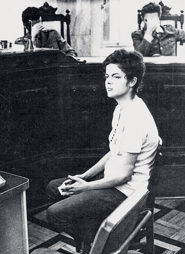 A RÉ DILMA Dilma na sede da Auditoria Militar no Rio de Janeiro, em novembro  de 1970. Ao fundo, os oficiais que a interrogavam sobre sua participação na luta armada escondem o rosto com a mão (Foto: Reprodução que consta no processo da Justiça Militar)